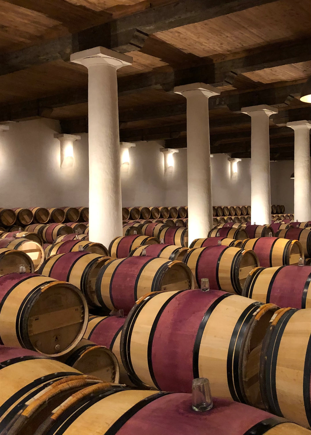 Vinný sklep s řadami dubových sudů určených ke zrání vína.